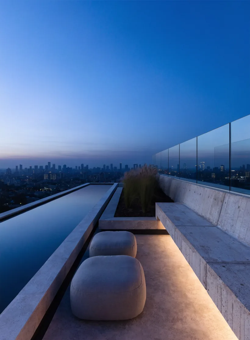 The private terrace of Residence 41 at dusk, the reflecting pool running to a frameless glass edge with the Dhaka skyline beyond